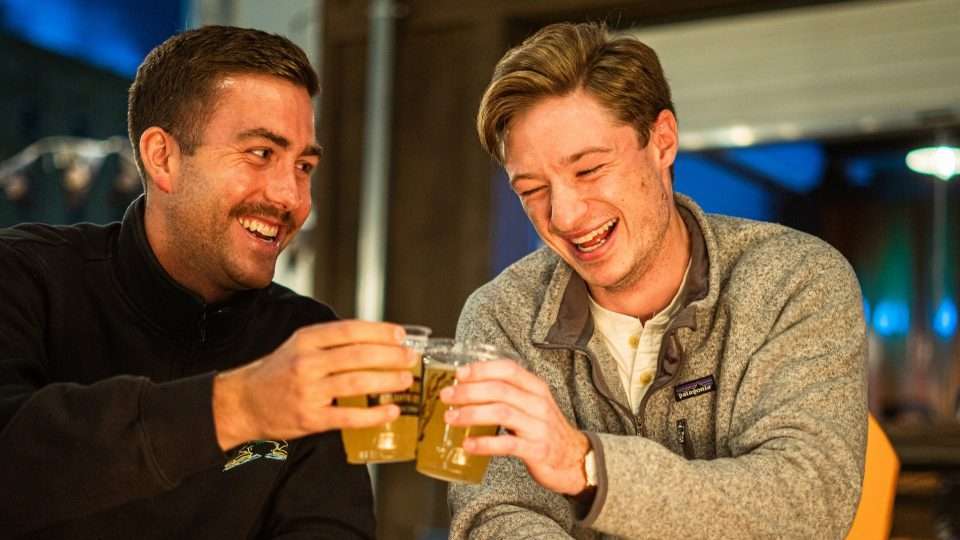 2 guys smiling and laughing enjoying beers