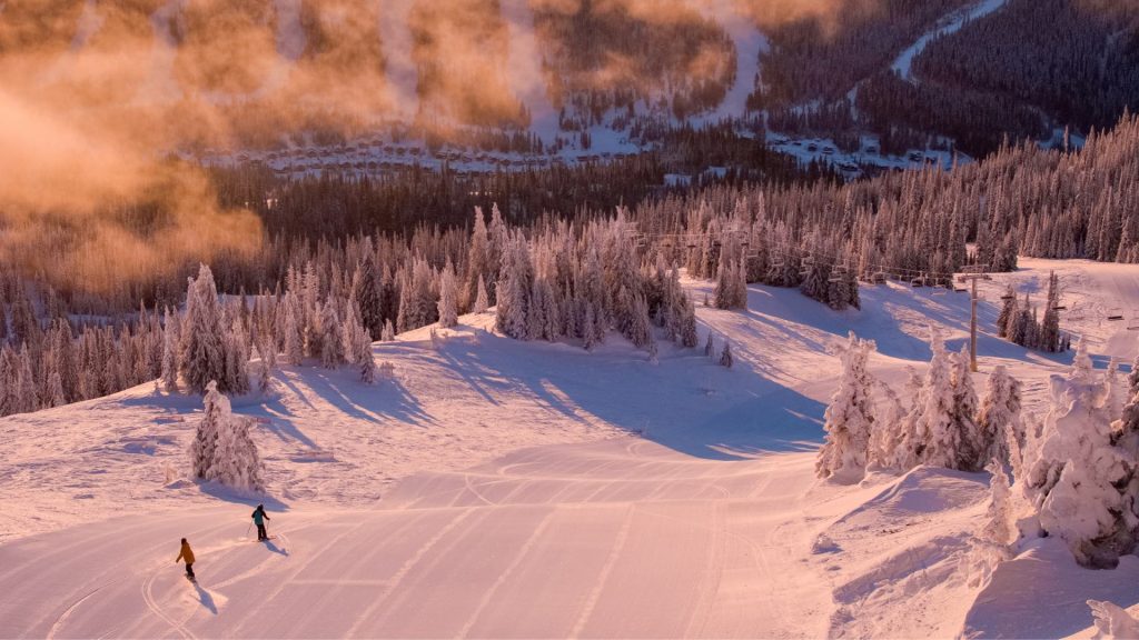 Skier and Snowboarder Making First Tracks on Freshly Groomed Sun Peaks Piste at Sunset