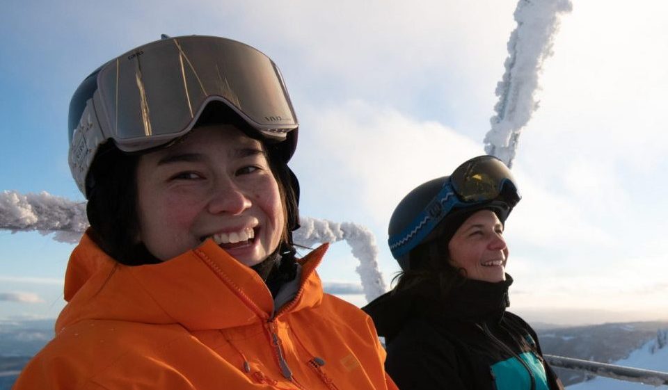 2 ski instructors on chairlift smiling