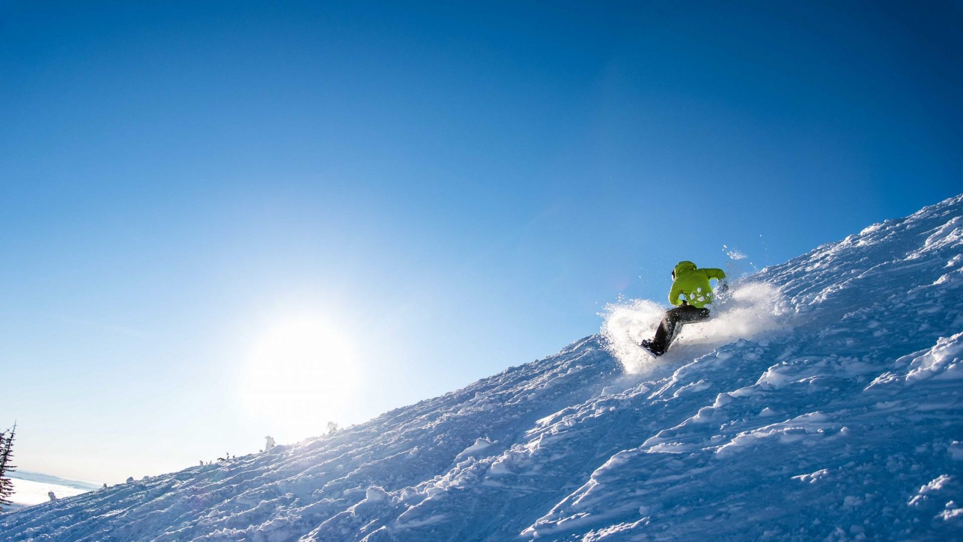 Snowboarder in green jacket skiing varied terrain