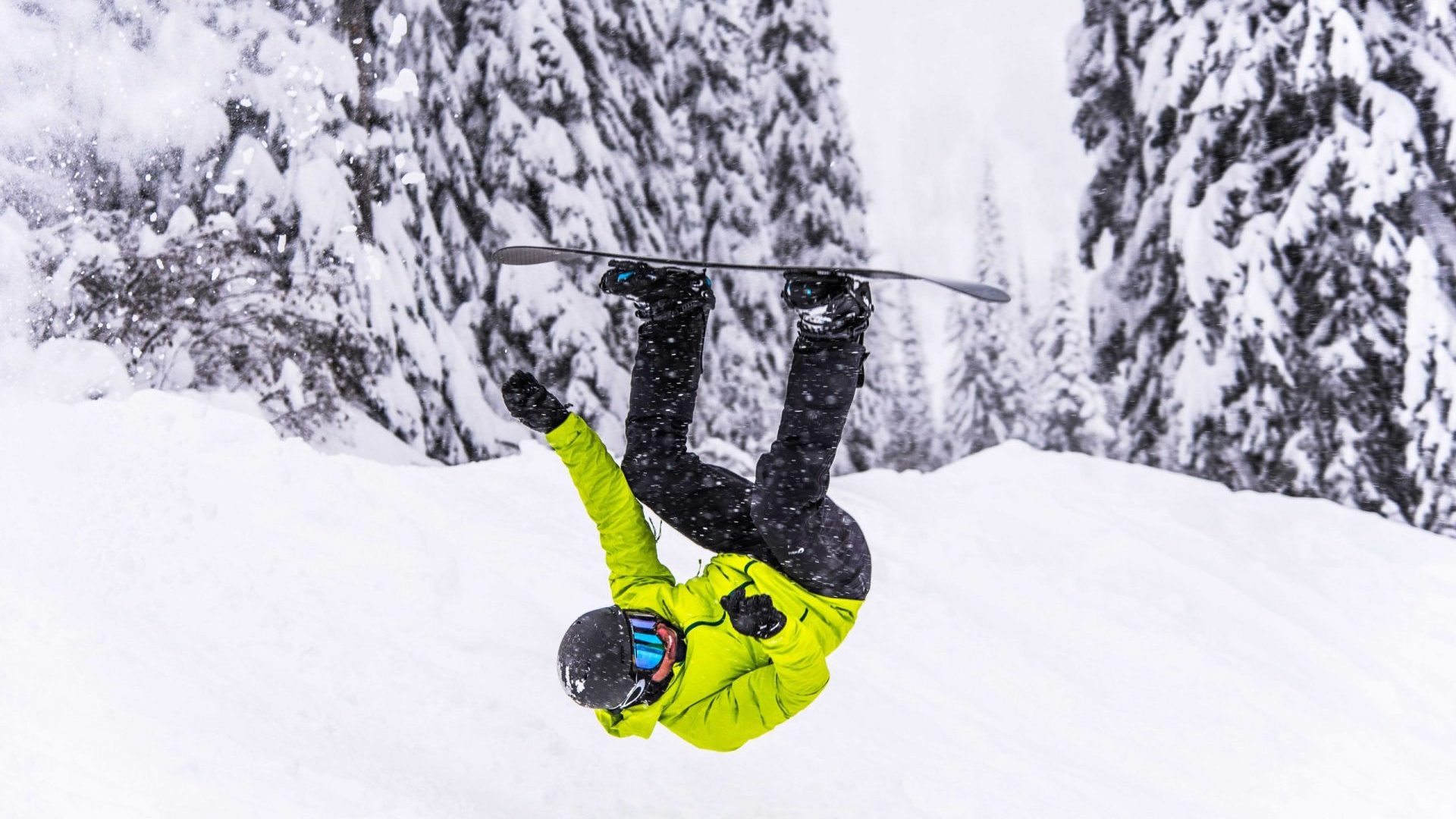 Snowboarder in green jacket performing flip