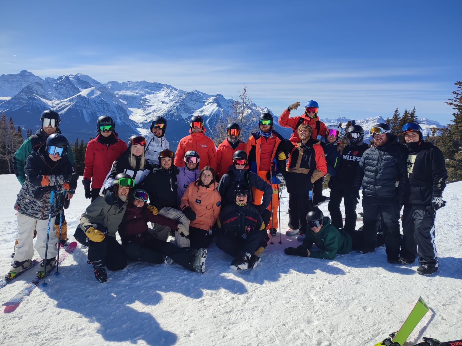 skiers and snowboarders on a mountain in a group smiling