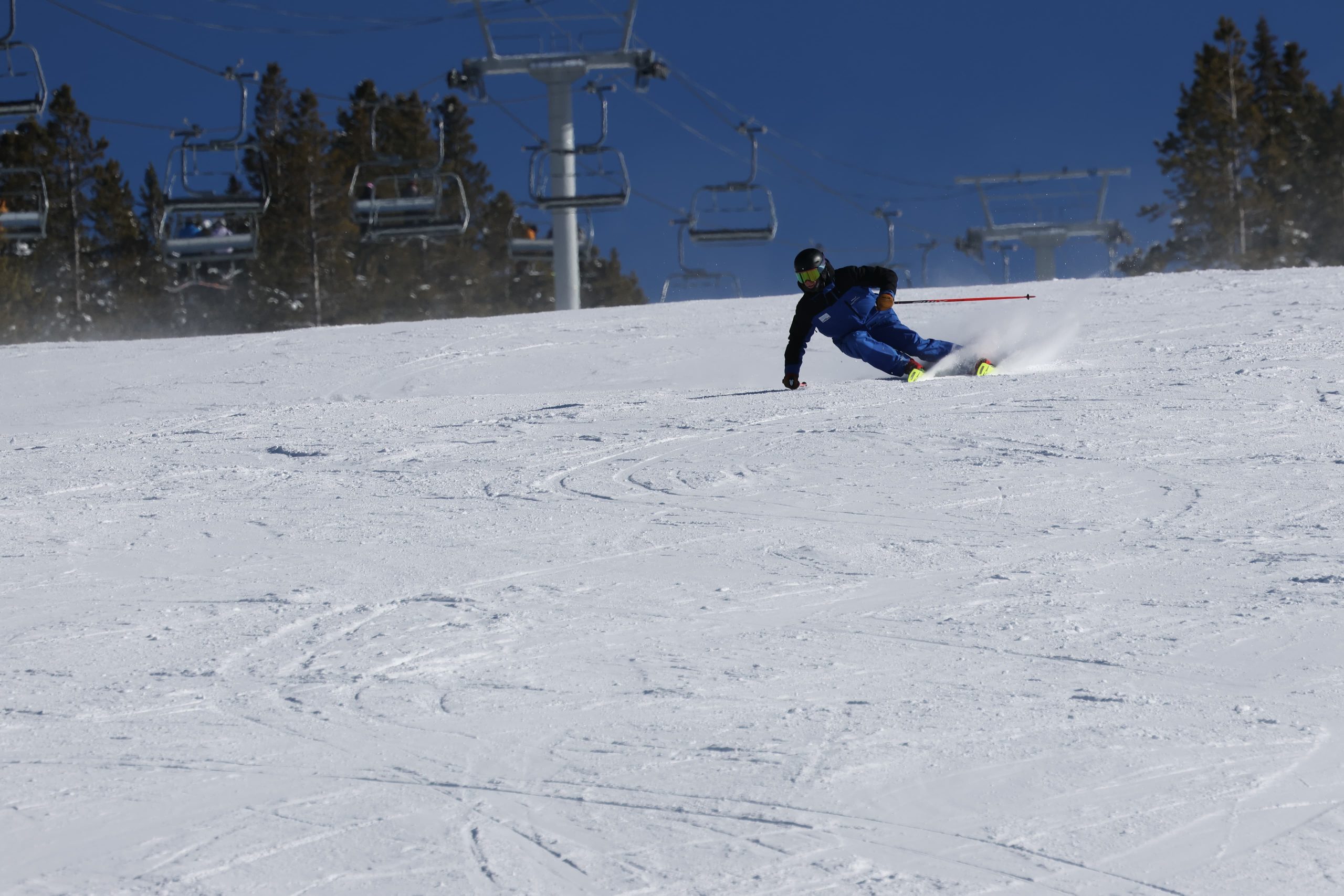 level 4 Skier in blue uniform carving down a ski run